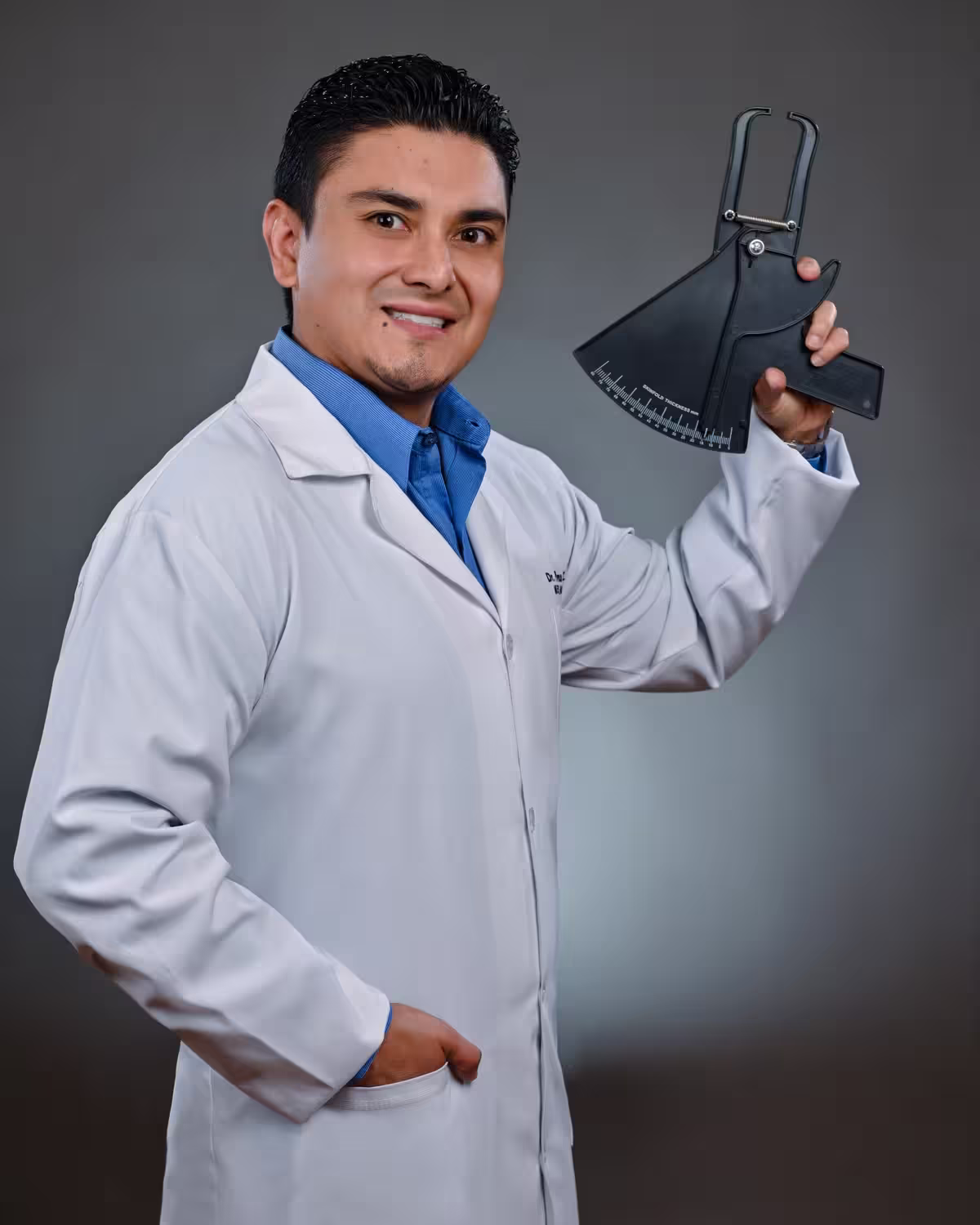 El Dr. Paul Alulema sosteniendo un adipómetro, instrumento de medición de pliegues cutáneos